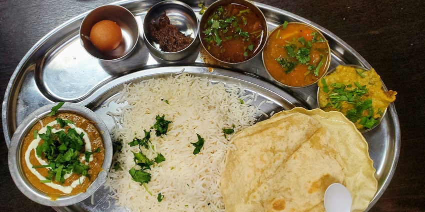 A tempting view of a silver plate served with delicious food options with a dessert.