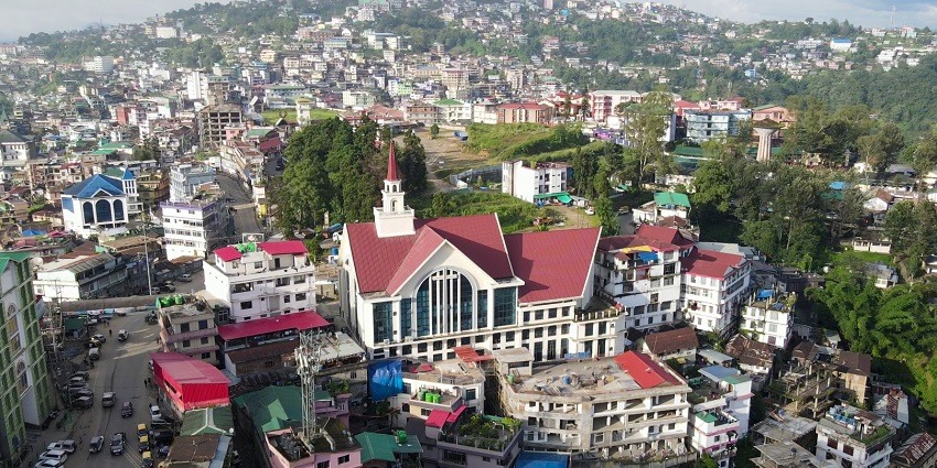 An aerial view of a hill city showing residential apartments and greenery