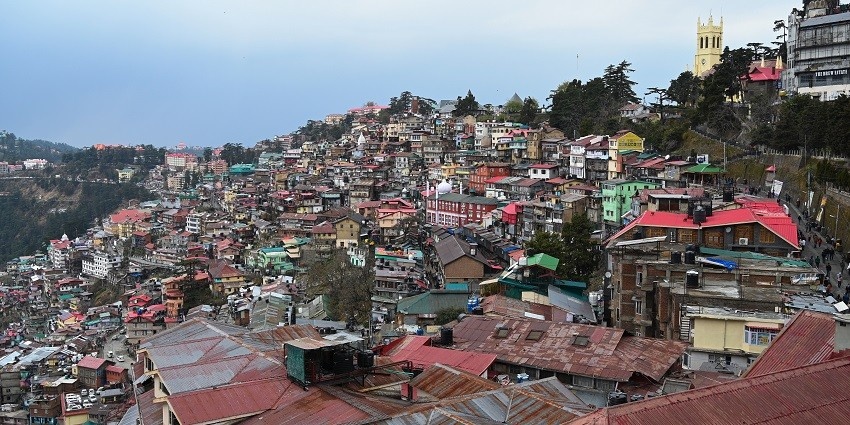 A picture of Shimla's cityscape with houses along the mountains and greenery