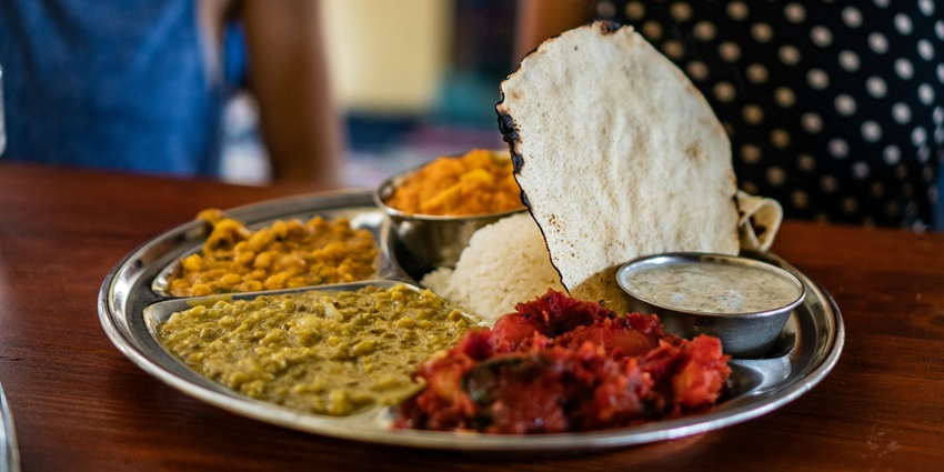 A mouth-watering view of a plate served with different cooked vegetables and papad.