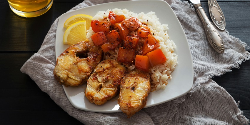 A mouth-watering view of a plate served with steamed rice topped with a cooked meat.