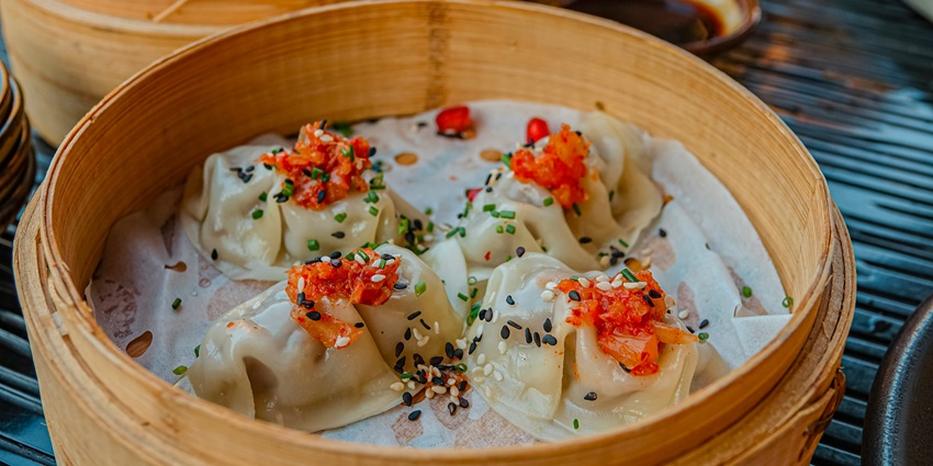 A tempting view of a brown pot with dumplings in it garnished with dip served on a table.