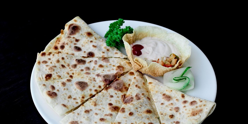 A tempting view of a dish served on a white ceramic plate with a dip on the side.