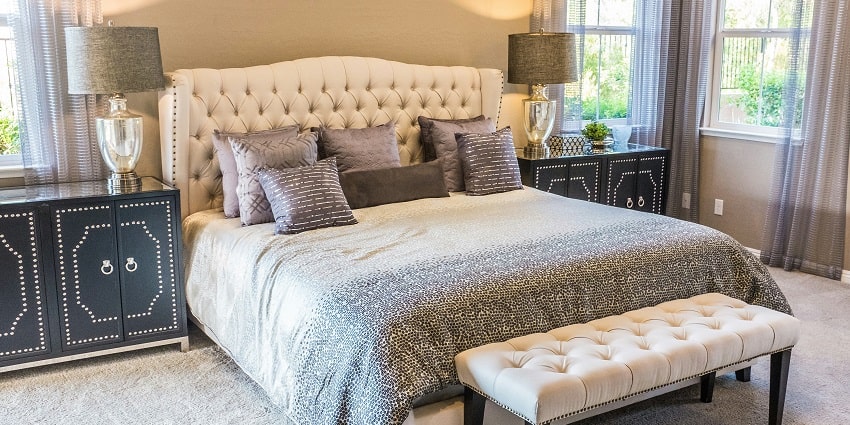 A fascinating view of a bedroom with a grey bed lined with white sheets and a couch.