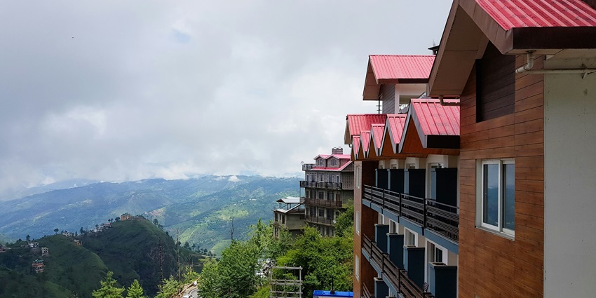 A mesmerising side view of a tall red building around greenery during the daytime.