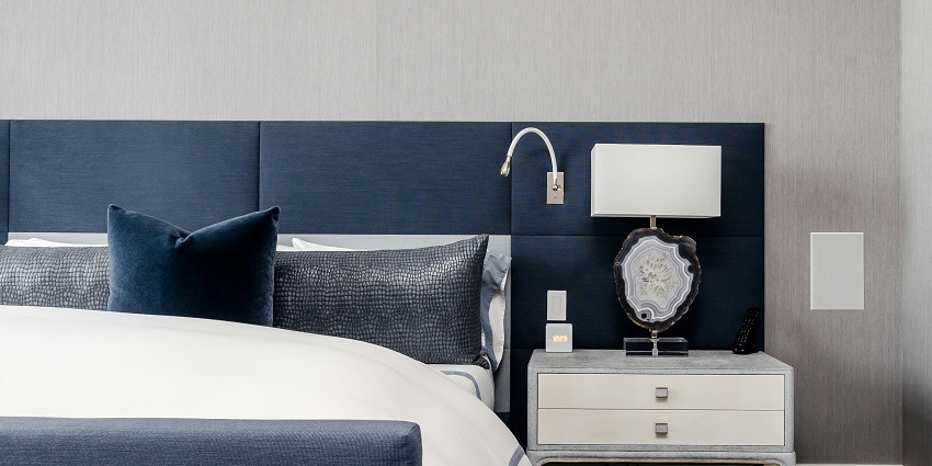A stunning view of a blue bed lined with white sheets and pillows on it during the day.