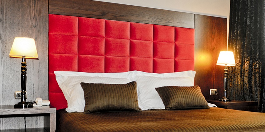 A picture of a hotel room with a double bed and lamps on both sides having a cosy ambience