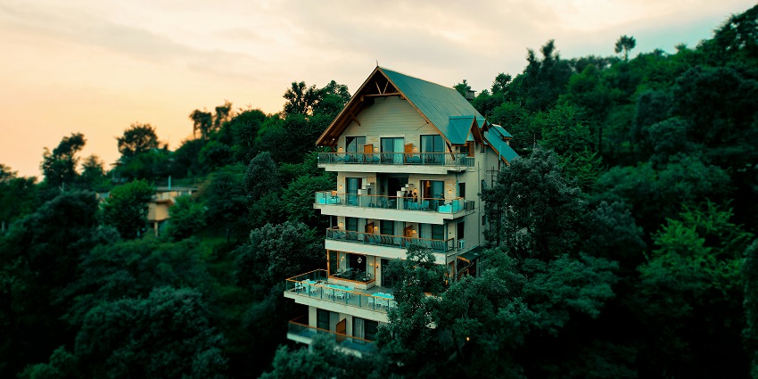 A stunning view of a hotel surrounded by lush greenery in Himachal Pradesh during the day.