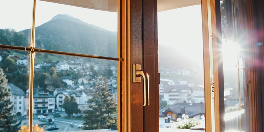 A view outside of a window of lush green hills, houses and trees during the daytime.