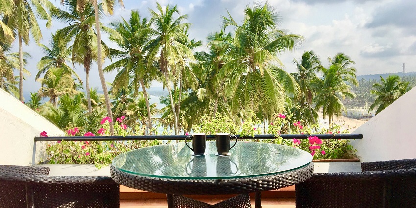 A mesmerising view from a hotel room with a glass table on the balcony with mugs.