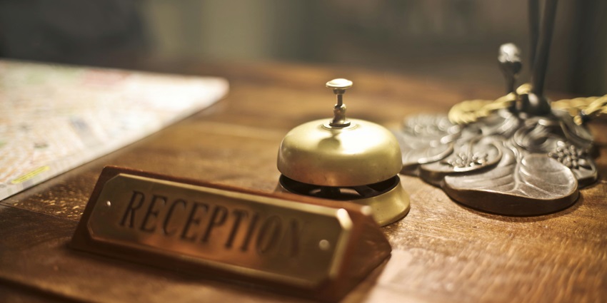 A unique view of an antique bell kept on a table with a golden board saying reception.