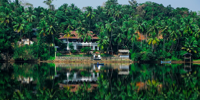 A breathtaking view of a house in Kerala surrounded by a water body and greenery.