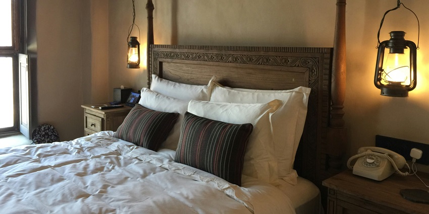 A mesmerising view of a room with a wooden bed lined with a white bedsheet and pillows.