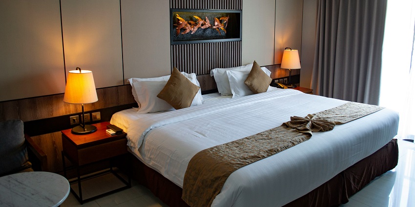 A view of a hotel room with a bed lined with white sheets and lamps on each side.