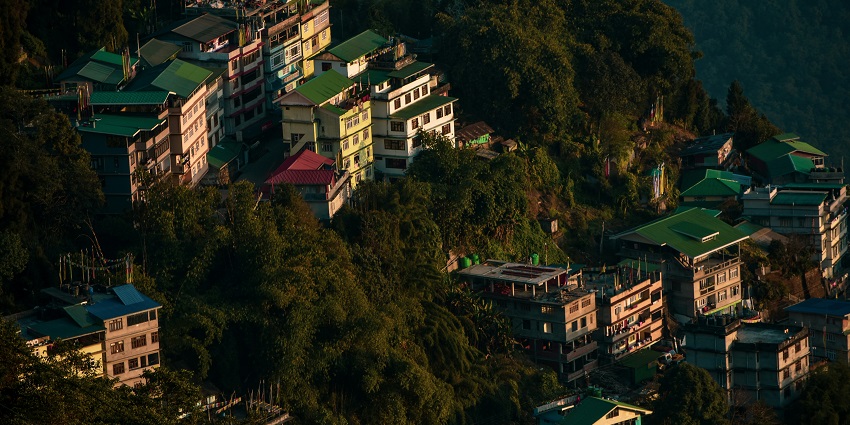 A stunning view of hotels in Gangtok surrounded by lush green mountains and trees.