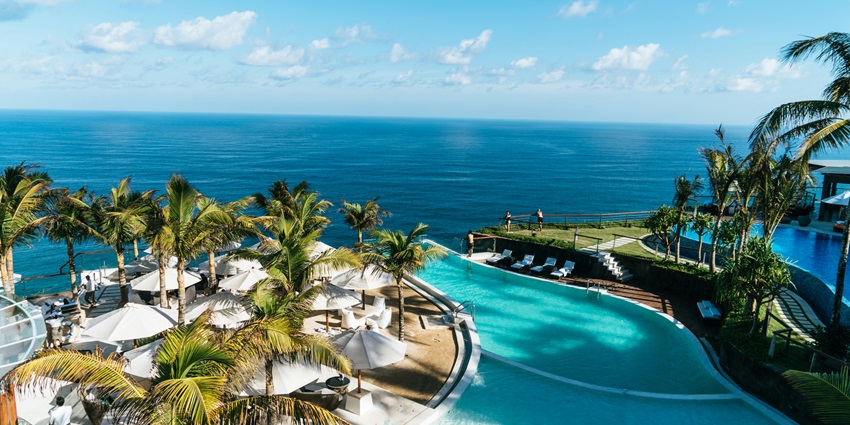 A breathtaking view of a hotel with a turquoise water body in front of it during the day.