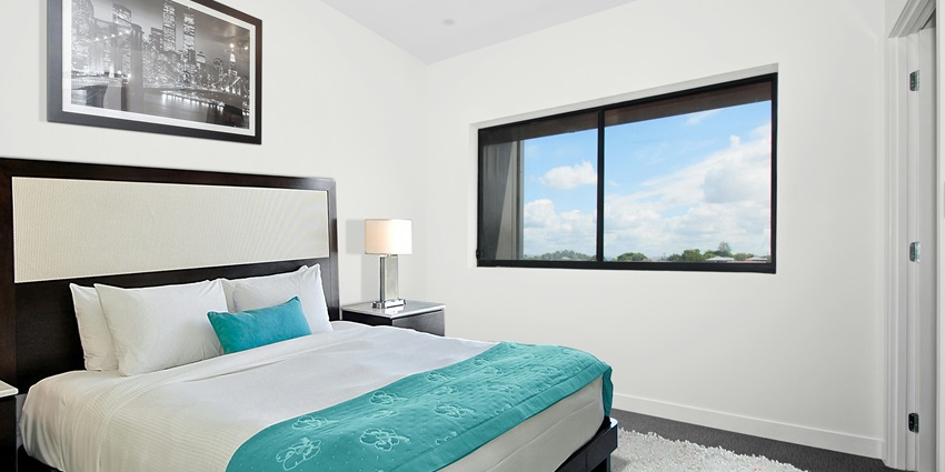 A stunning view of a room with a bed lined with white and blue sheets and a lamp.
