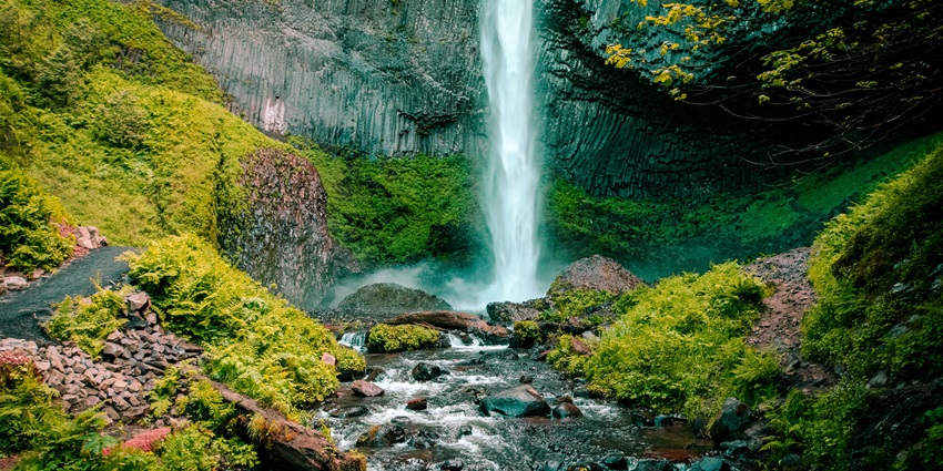 A mesmerising time-lapse image of a multi-tiered waterfall cascading down rocks surrounded by greenery.
