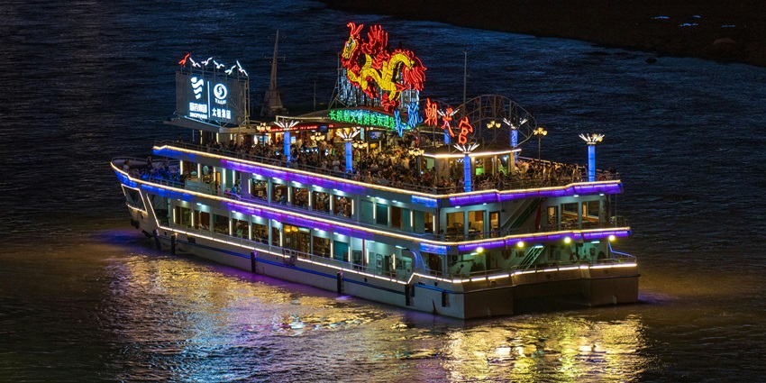 Image of a boat decorated with lights at night and people on board partying and dancing