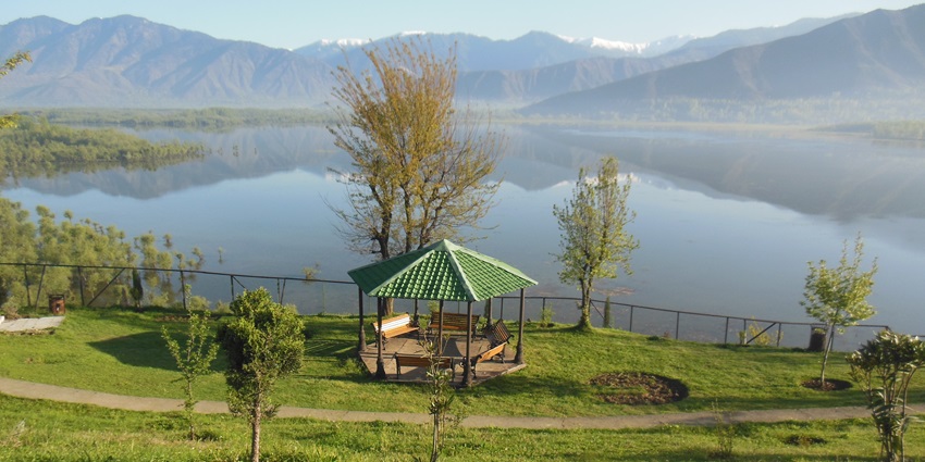 A scenic view of Wular Lake with the backdrop of the mountains and lush greenery