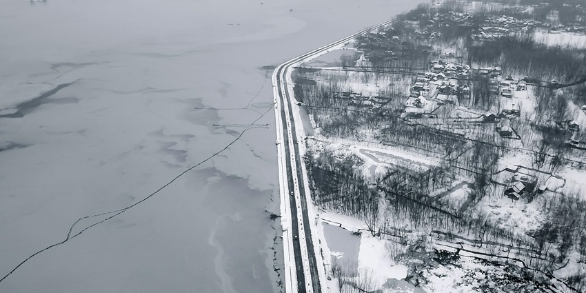 A breathtaking aerial view of a lake in Kashmir covered under thick snow during the day.
