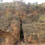 Scenic view of Yaganti Cave in Kurnool, surrounded by lush greenery and rocky hills.