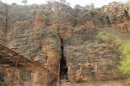 Scenic view of Yaganti Cave in Kurnool, surrounded by lush greenery and rocky hills.