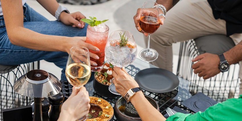 Friends toasting with alcoholic drinks, glasses raised in cheerful celebration.