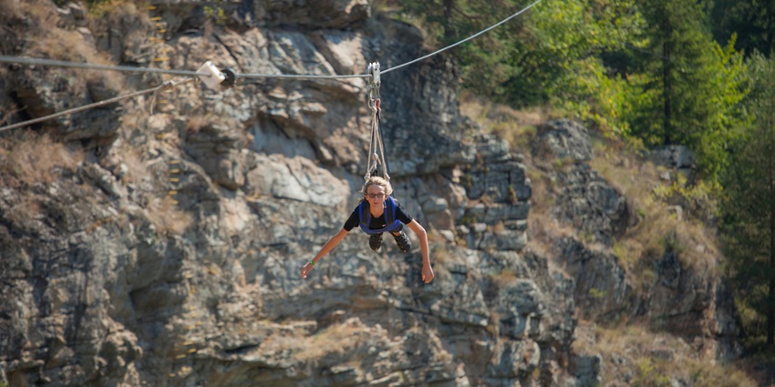 Thrilling zipline adventure captured mid-air over a rocky canyon, with the rider suspended above dramatic terrain, one of the best things to do in Dalhousie in October.