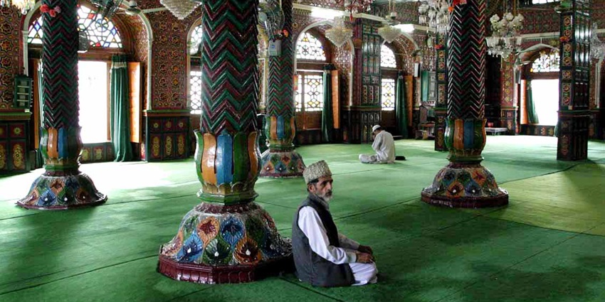 A picture of the interiors of a religious site with decorated pillars and chandeliers