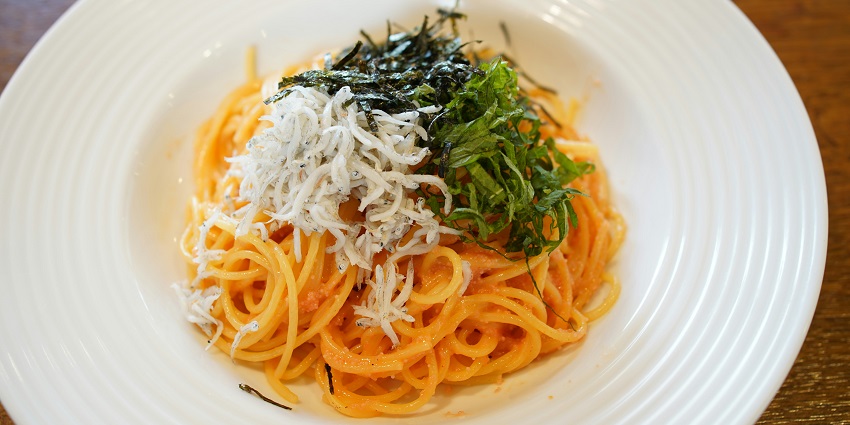 A mouth-watering view of a dish served with noodles and garnished with cheese and greens.