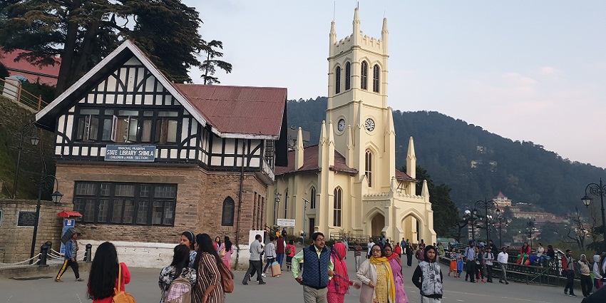 A picture of a church taken from a distant street with people commuting