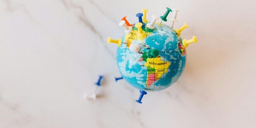 A mesmerising view of a blue globe with different colourful push pins on it on a table.