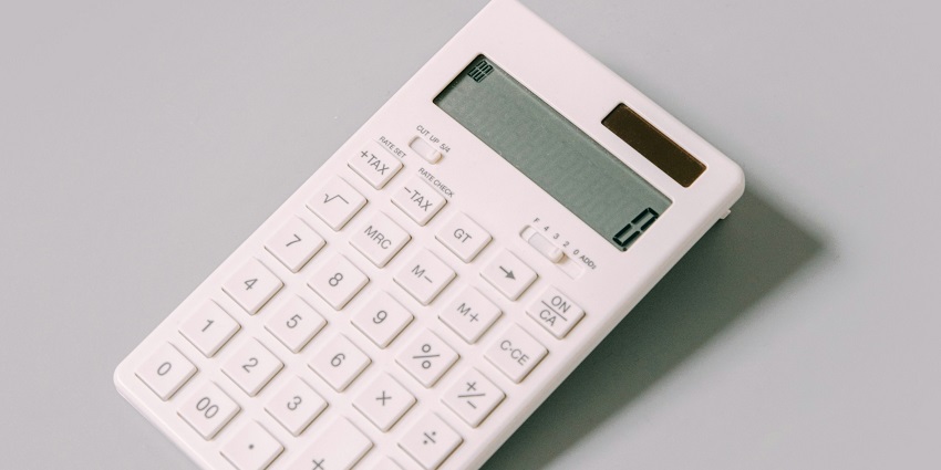 A focused view of a white calculator with a black number saying zero on a white table.