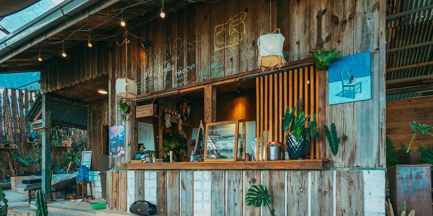 Wooden beach bar with a thatched roof and a view of the sandy shore.