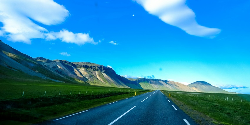 Serene asphalt road winding through mountains, capturing nature's beauty.