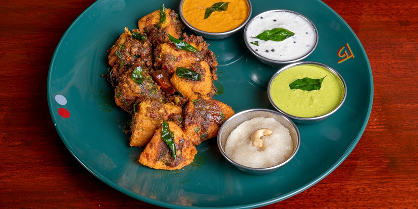 A mouth-watering view of a plate of served with three types of dips and a dessert.