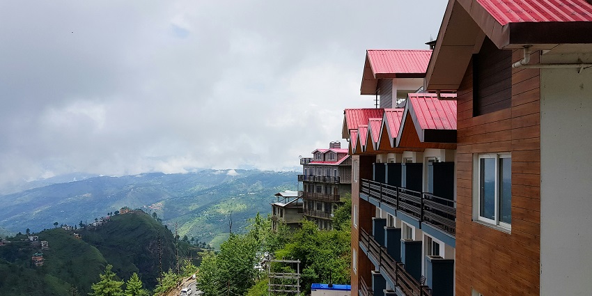 A stunning side view of a red hotel in Himachal Pradesh where you can enjoy a stay.