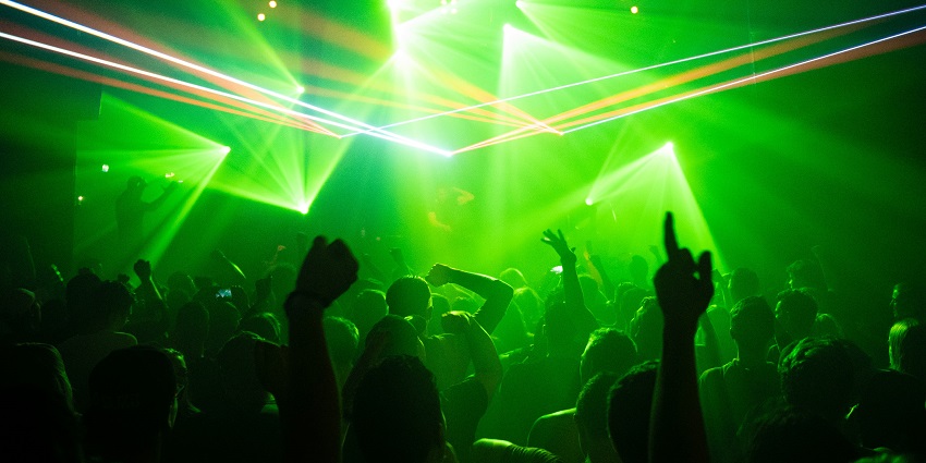 A view of people dancing to the whimsical music accompanied by vibrant neon lights.