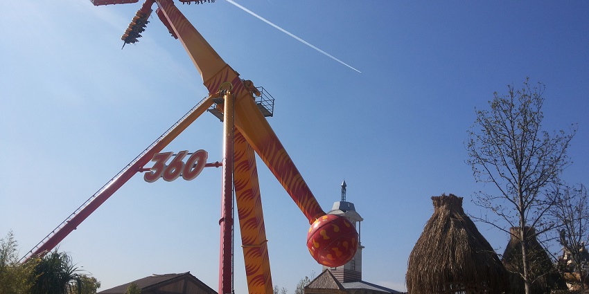A picture of an adventurous 360 degree ride at an amusement park taken on a sunny day