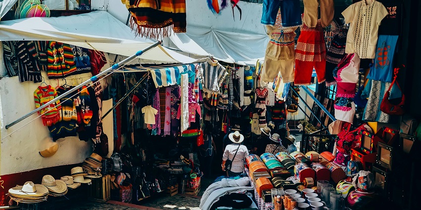 An image of Busy Adalat Bazaar with colourful stalls displaying Phulkari embroidery and traditional Punjabi juttis.