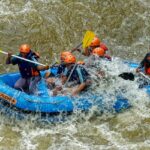 A breathtaking view of a few men enjoying river rafting in a body of water during the day.