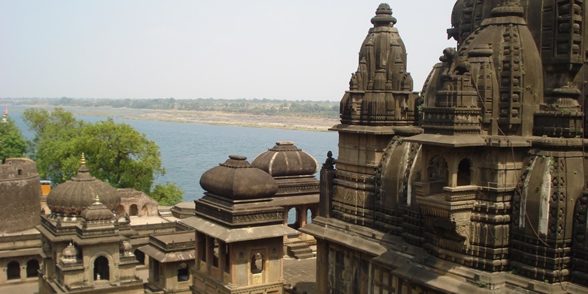 A side view of a brownish ancient architecture that is located on the bank of a river