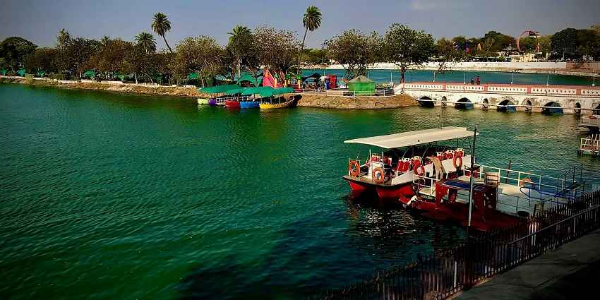 A breathtaking view of a lake in Ahmedabad with lush greenery all around during the day.