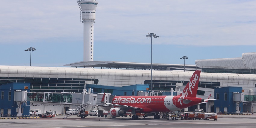 Image of Kuala Lumpur International Airport terminal with planes and modern architecture.