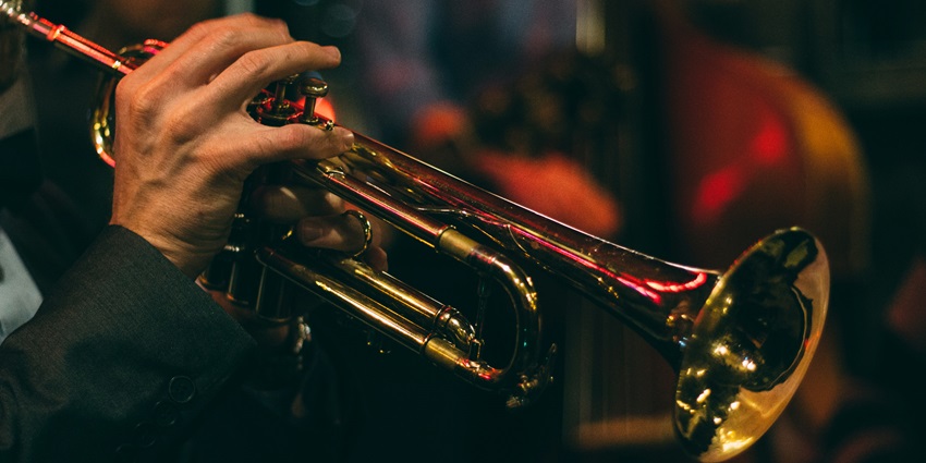 A close-up shot of a person playing a trumpet at a venue during the evening time.