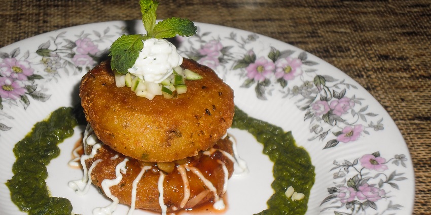 A delicious plate of aloo tikki served on white plate, one of the best street food in Chandigarh.