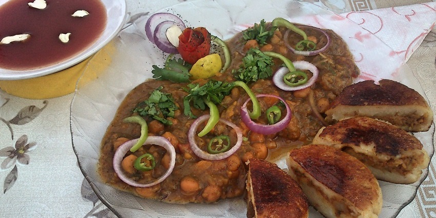 Aloo Tikki is served with cole spicy chickpea curry and garnished with onions