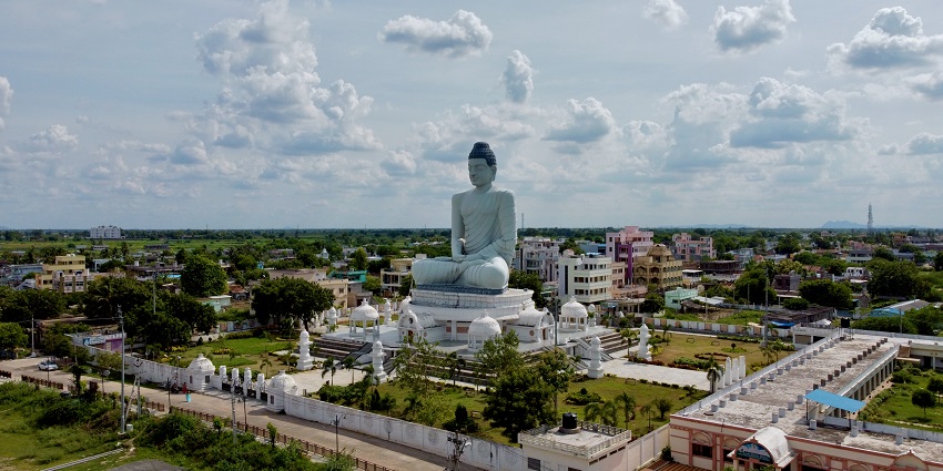An aerial picture of a Buddha statue places in the middle of a garden surrounded by greenery