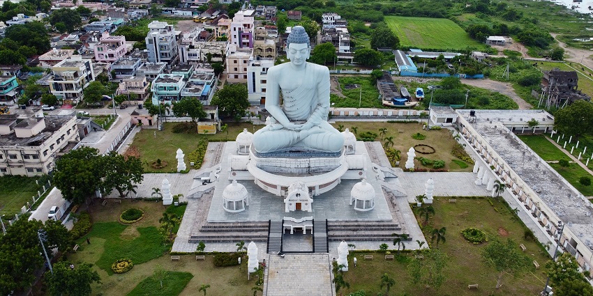 An aerial view of a tall Buddha statue situated in the centre of a garden with greenery all around